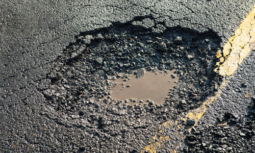 Close up image of a pot hole that has damaged the road surface